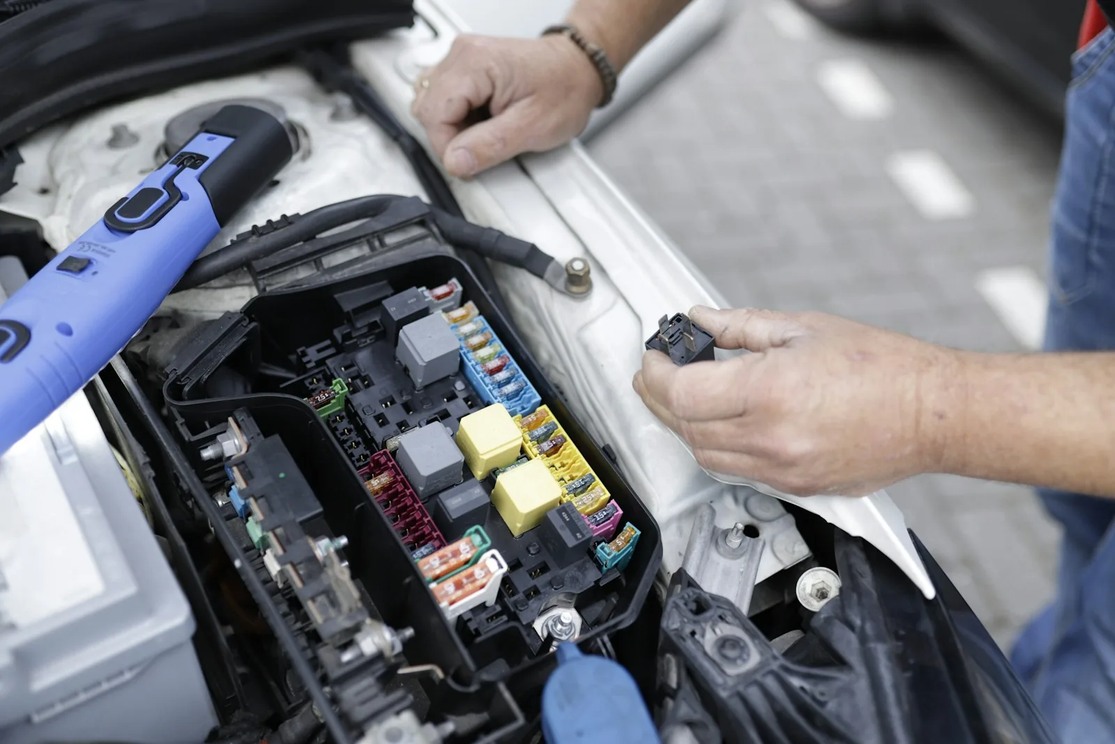 Anonymous hands working on an automotive fuse and relay system