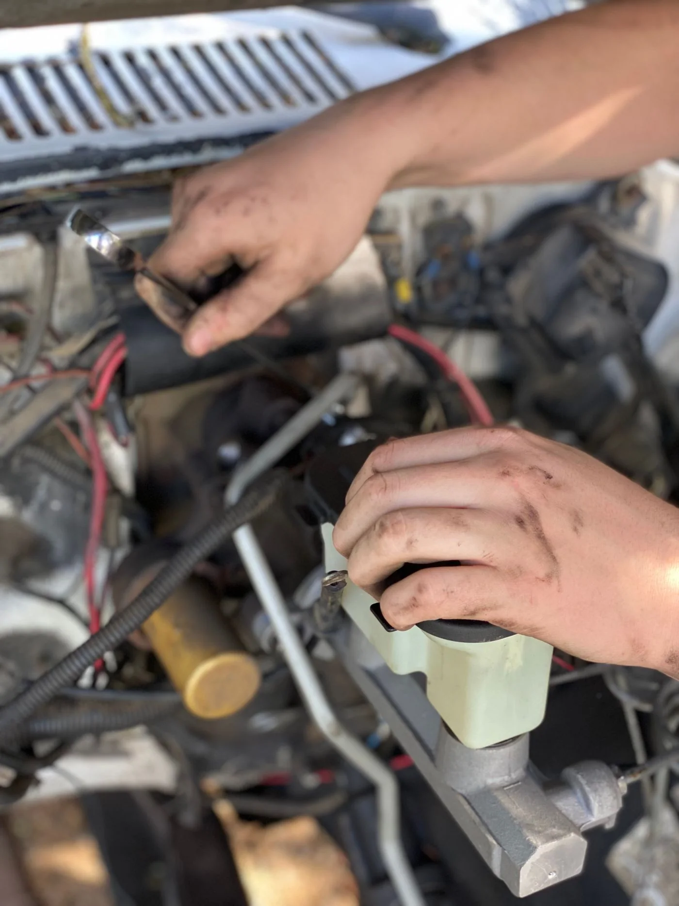 Anonymous hands carrying out detailed electrical work in an engine bay