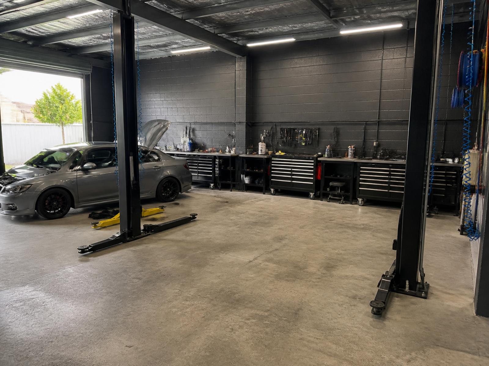 Wide view of a clean, organised independent automotive workshop with service bays and tool cabinets